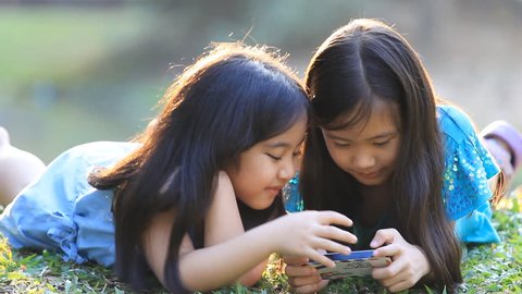 Asian girls playing a game on smart phone together in the park