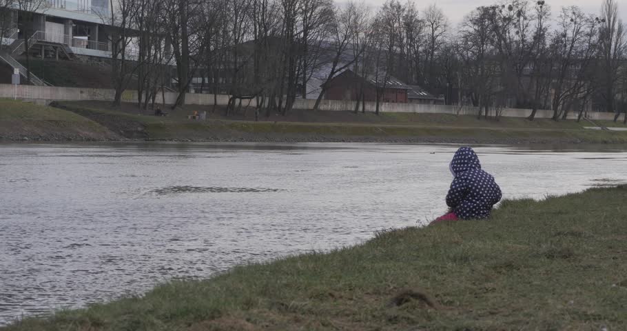 little girl fishing with a fishing rod in the winter fishing in winter clothes, a cap, a jacket. Autumn Spring. Evening at sunset.