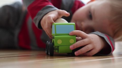 little boy plays with his toy wood truck