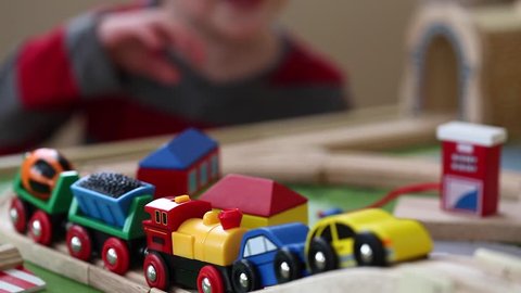 a boy playing with his toy trains and cars on track