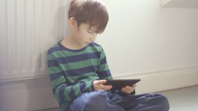 Young boy engrossed in playing games on a touchscreen tablet