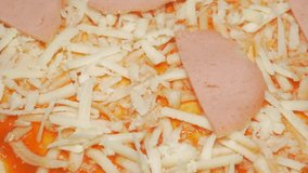 Pizza base covered with cheese and salami slow 4K 2160p UHD panning footage - Grated cheese and ham all over pizza base close-up 4K 3840X2160 UHD panning video