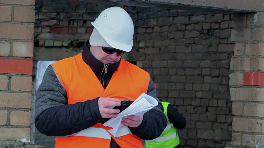 Construction foreman with tablet PC near unfinished building