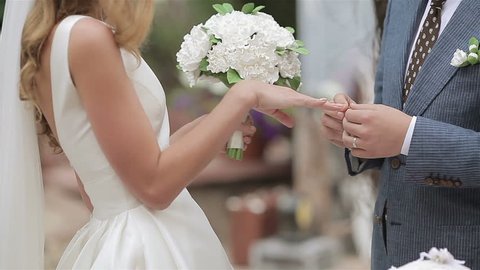 On a wedding day groom puts a wedding ring on finger of a bride. Bride puts a ring on finger of a groom