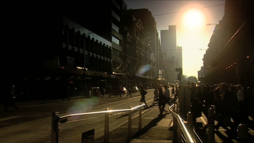 Early morning pedestrians cross a busy street intersection at a Melbourne City tram stop outside on Flinders Street out side Flinders Street Railway Station