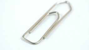A metal paper clip on the table. With the camera turning around to view the clip