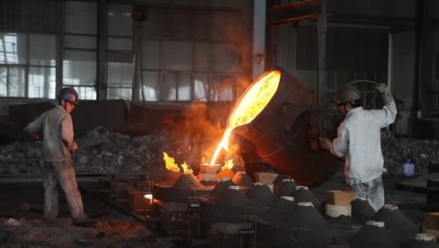 Shanghai,China-July 10,2012: chinese metallurgy worker pouring melting steel liquid into the mold.