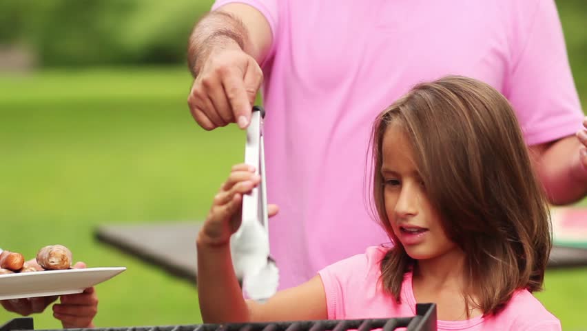 family taking food off grill and getting ready to eat