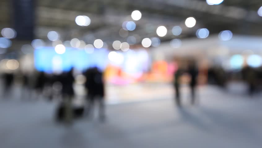 People walk visiting a trade show, generic background. Intentionally blurred post production.