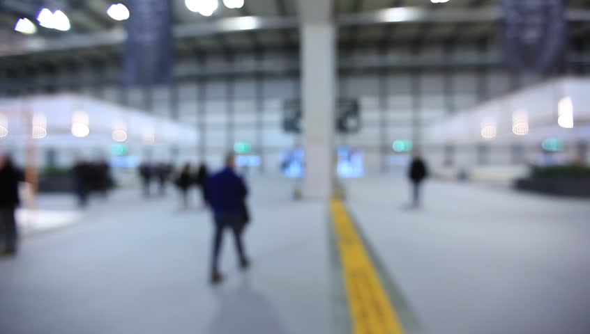 People walk visiting a trade show, generic background. Intentionally blurred post production.