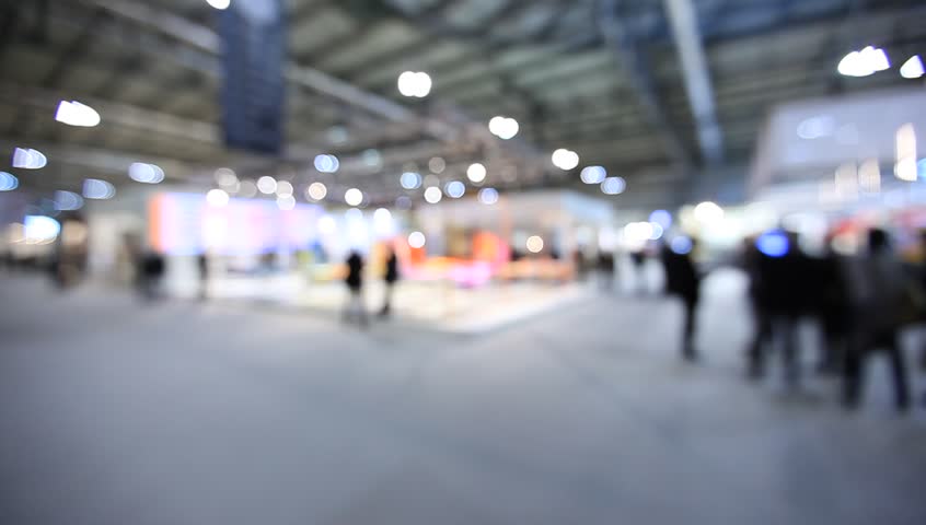 People walk visiting a trade show, generic background. Intentionally blurred post production.