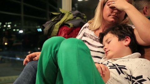 Tired mother and son sleeping  on the airport, waiting for her flight