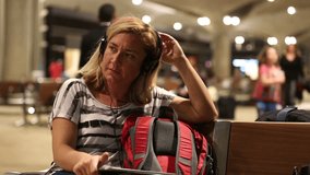 middle age blonde women listening music digital tablet at airport
