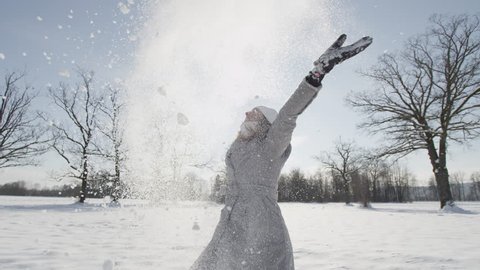 SLOW MOTION: Happy young woman playing with snow
