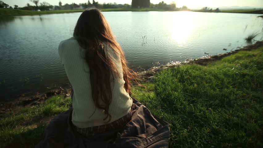 Lonely brunette young lady on the river bank. 