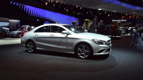 BRUSSELS, BELGIUM - JANUARY 15: Silver Mercedes Benz CLA sedan on display at the 2015 Brussels Motor Show. People in te background are looking at the cars.