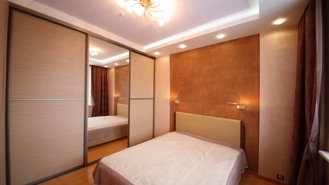 Turn on/off light in bedroom with closet, large mirror and beige double bed