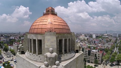 Aerial shot of the dome of the Monumento a la Revolucion with city buildings on the back in a sunny day in Mexico City