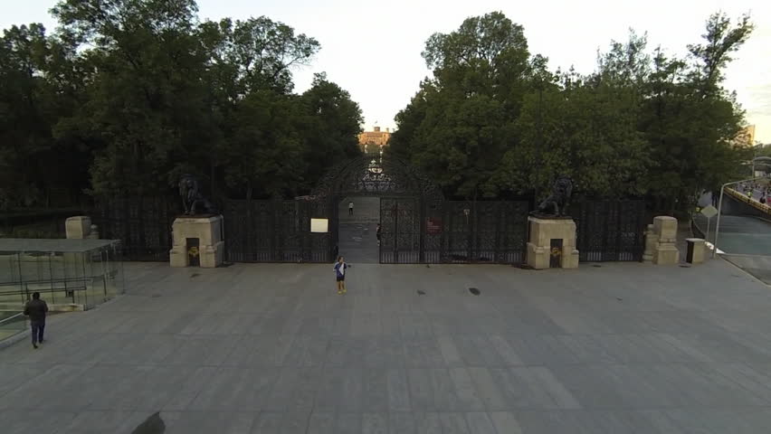 Aerial shot of the Lions Gate in Chapultepec forest, view of some people running across the forest with the big and beautiful Chapultepec Castle behind in the sunrise at Mexico City