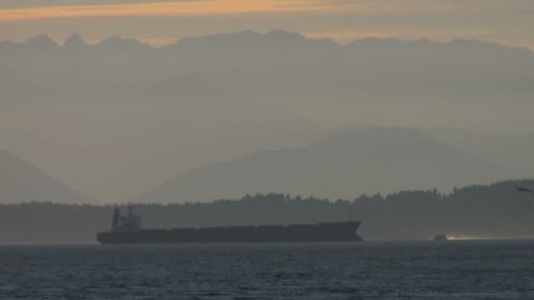 A large ship on a hazy day with misty mountains in the distance