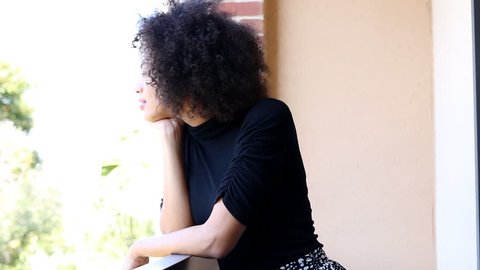 Sad young african american woman waiting on balcony