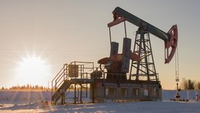Oil pump (pump-jack, nodding donkey) in Russia. Sunny weather. Evening lighting. Winter. The footage was created from RAW sequence due to additional software for the camera. Real time. Looping.