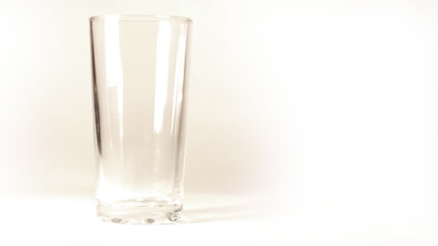 mineral water is poured into a glass on white background - slow motion