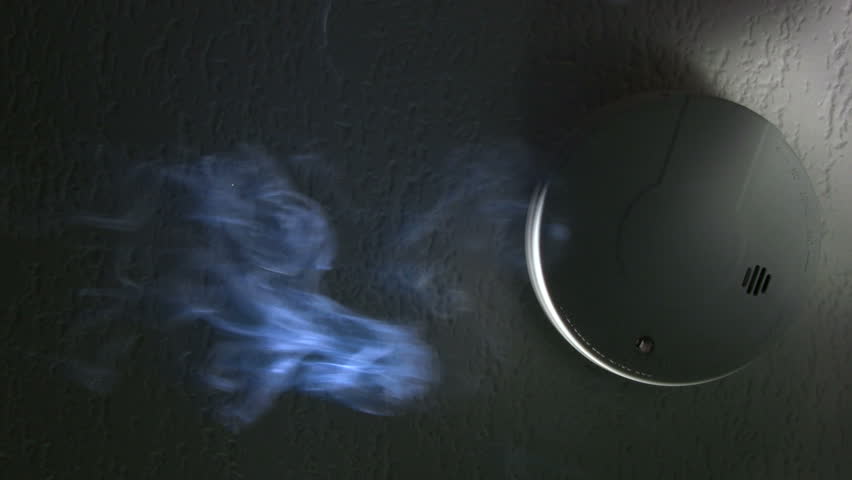 Smoke passes through a ceiling mounted smoke detector causing its activation