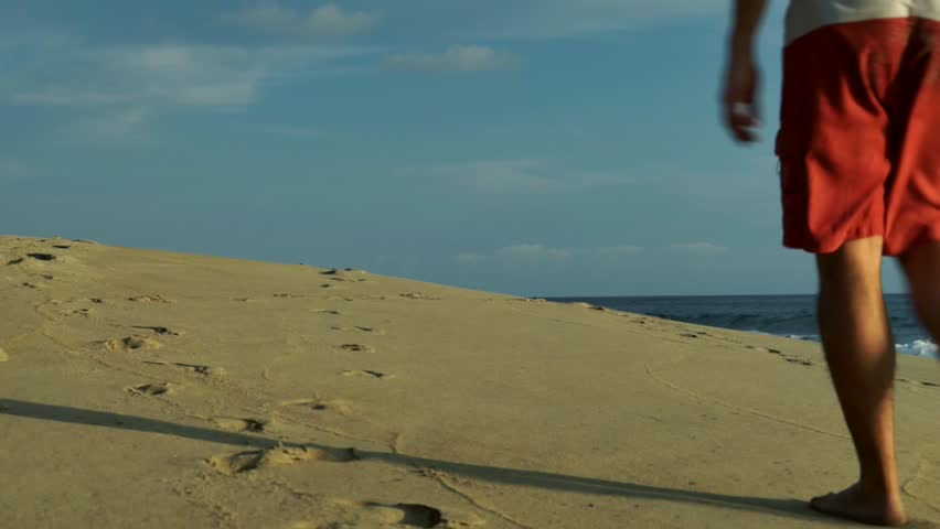 man walking on a dune on the beach
