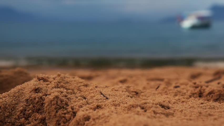 Close up of sand and unfocused turquoise water in background 