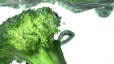 Green Broccoli. Green broccoli florets slowly fall into the water on a with background. Slow Motion