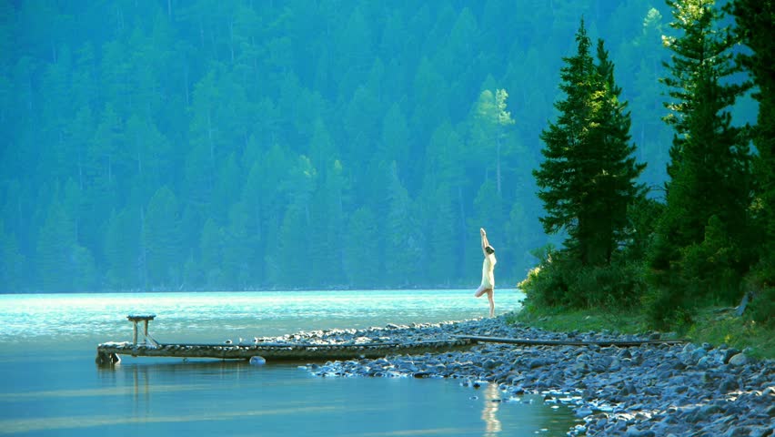 Girl relaxing on the lakeside in the mountains. Perfect smooth seamless loop.