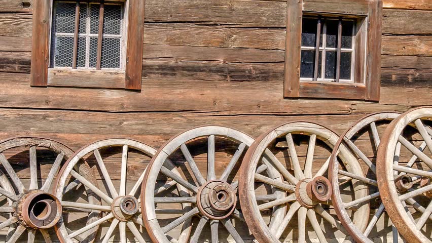 Old wooden house with wooden wagon wheels in front
