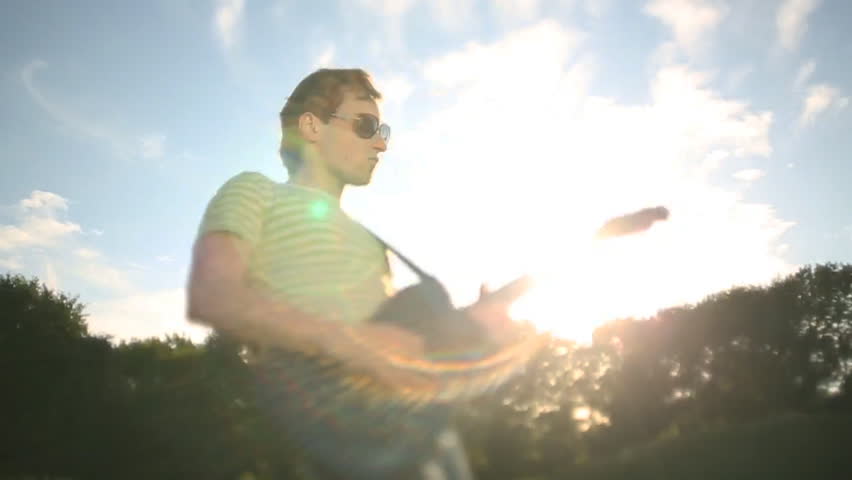 Portrait of a handsome young man with a guitar outdoor