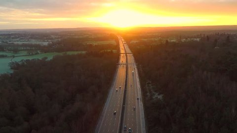 Aerial view of a truck and other traffic driving along a road at sunrise 