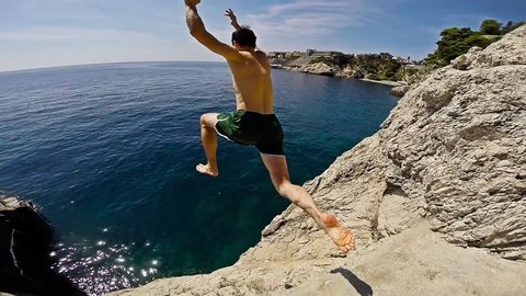 Athletic Young Man Jumping From Cliff Into Ocean Sea Water Muscular Adventure Extreme Sports Lifestyle Hobby Vacation Clear Beach Slow Motion Leisure Activity Gopro HD