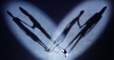 5K Top view of couple on the ice standing in heartshape spotlights, they starting romantic dance and their shadows reflecting on the ice