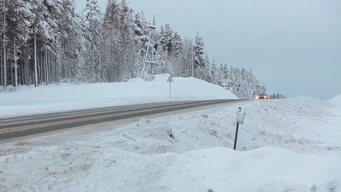 Fast driving car on highway at winter season, snowfall over forest. Karelia, Russia