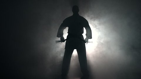 Young man with muscled body, training martial arts (Goju-Ryu Karate-Do) in silhouette