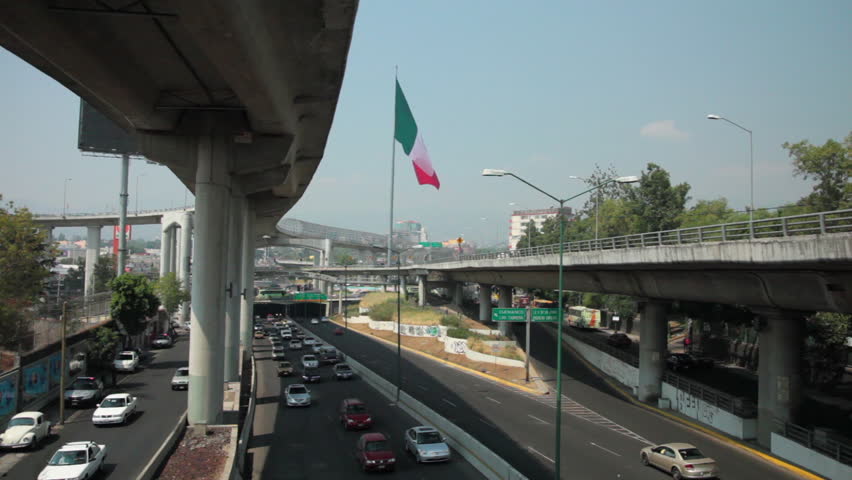 Urban landscape in Mexico City showing the peripheral freeway and the Mexican Flag.
