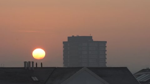 Sunrise, Chelsea Harbour, London, late January, with large bird flying across sun's disc at 13s