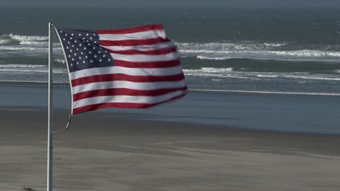 American Flag blowing as strong winds reach the beach of the Pacific Coast in Seaside, Oregon.