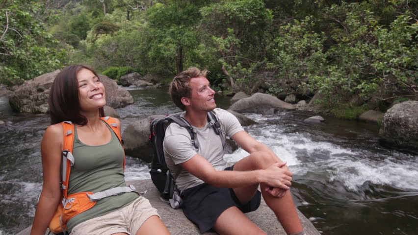 Hiking people in outdoor activity wearing backpacks relaxing. Hikers, woman and man hiker looking with smiling happy. Healthy lifestyle image from Iao Valley State Park, Wailuku, Maui, Hawaii, USA.