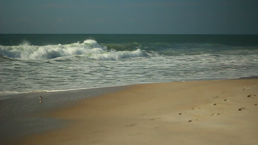 Waves break on a sandy beach in the summer.