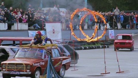 KIEV, UKRAINE - SEPTEMBER 29, 2013 - Bigfoot Crash Show. Stuntman on top of car jumps through fire circles, sequence