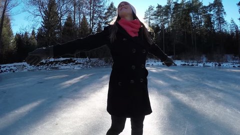 Smiling young woman spinning on ice skates in sunny forest