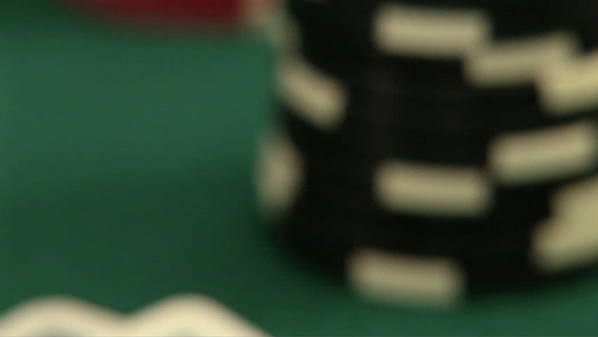 Hand holding pocket aces  in a deck of playing cards with poker chips
