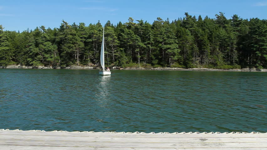 A man sailing his boat in a cove.  