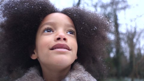 Little girl in wonder at the snowflakes falling around her outdoors