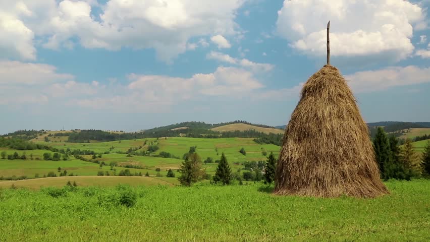 Clouds and haystack on green field